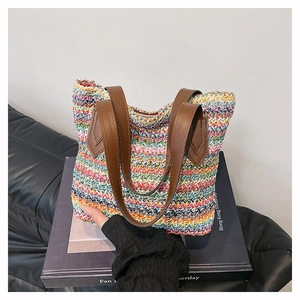 Close-up of multicolored woven straw tote bag with brown faux leather shoulder handles