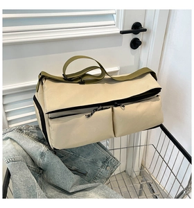 Detail of cream travel bag with olive green straps featuring functional front zipper pockets