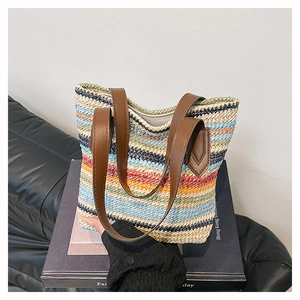 Detail of colorful striped straw tote bag with brown leather handles and zipper closure