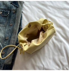 Detail view of yellow leather bucket bag with magnetic closure and beige fabric lining