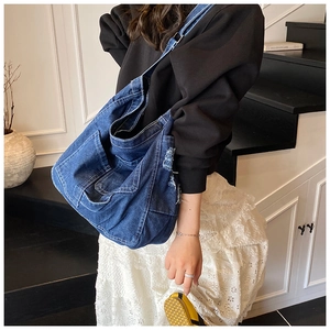 Detail of blue denim tote bag showing distressed edges and large capacity on model