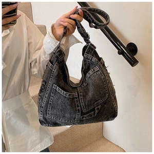 Detail of washed denim tote bag featuring multi-pocket design and white topstitching