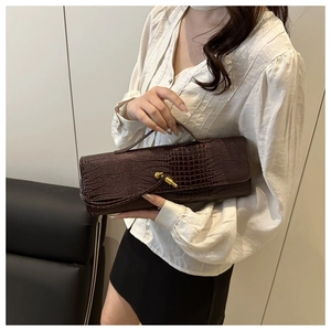 Detail showing the dark brown crocodile pattern handbag with its golden metal twist lock clasp