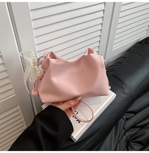 Close-up of pink ruched bucket bag with pearl handle and elegant white lace bow charm