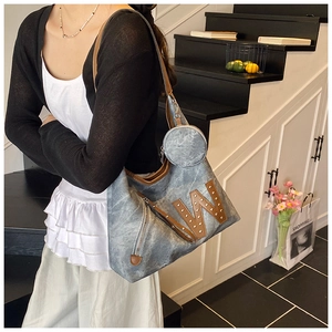 Detail shot of blue tote bag featuring a leather W letter patch and metallic rivets