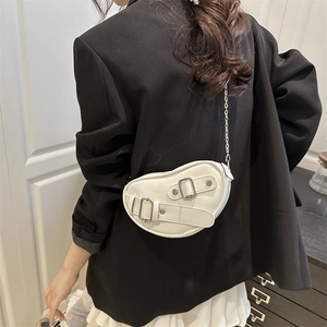 Sac bandoulière demi-lune blanc moderne avec chaînes argentées sur un blazer noir élégant