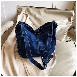 Detailed view of dark blue washed denim tote bag with multiple pockets and frayed edges