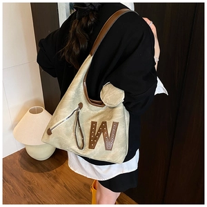 Detail of khaki tote bag with textured leather, brown trim, and letter W emblem