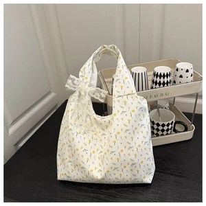 Detail of floral canvas tote bag featuring lace bow decoration and yellow flower patterns