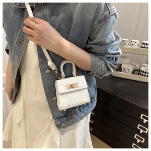 Detailed shot of white faux crocodile leather mini bag with gold lock on a model