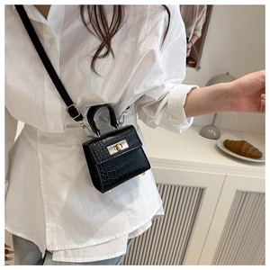 Detail shot of black crocodile pattern leather texture and metallic twist lock on mini bag