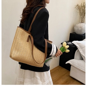 Détail du grand sac cabas en paille avec anses en cuir marron porté par un mannequin chez soi