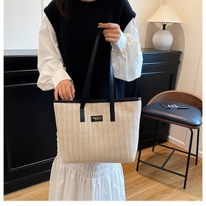 Détail du sac cabas en paille tressée avec garnitures en cuir noir et étiquette mode