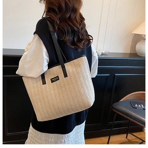 Détail du grand sac cabas en paille avec garniture en cuir noir et écusson tendance