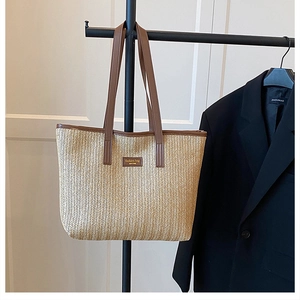 Détail d'un sac cabas en paille tissé avec lanières en cuir et étiquette tendance
