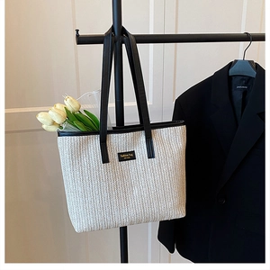 Détail de la texture d'un grand sac cabas en paille avec étiquette et anses en cuir