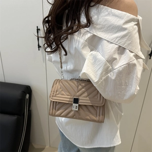 Fashionable beige quilted crossbody bag with silver chain strap shown on model's shoulder