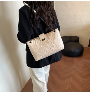 Dettaglio della borsa a catena beige trapuntata con chiusura a scatto e tracolla intrecciata