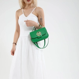 Fashionable bright green crossbody bag with metal M buckle shown by model in white dress