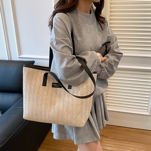 Sac fourre-tout minimaliste en paille tissée avec anses en cuir noir et étiquette mode