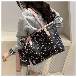Detail of black tote bag with pink bow pattern and matching small hanging pouch