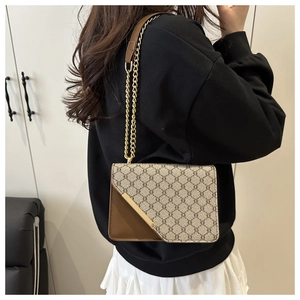 Detail of a brown and beige patterned crossbody bag with gold chain and metal buckle