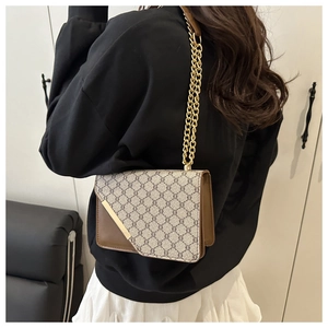 Detail of vintage crossbody bag showing brown leather texture and gold chain strap