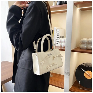 Vue détaillée du sac à main beige avec nœuds et perles porté par un mannequin