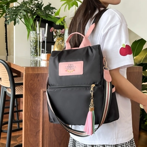 Sac à dos noir en nylon imperméable avec détails roses et sangle colorée porté par un mannequin