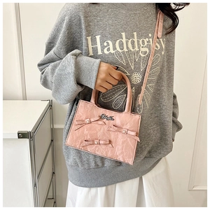 Détail du sac bandoulière rose plissé avec nœuds décoratifs et ornements en perles