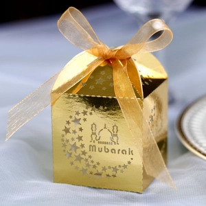 Detailed laser-cut Mubarak gold favor box with moon and star patterns and satin ribbon