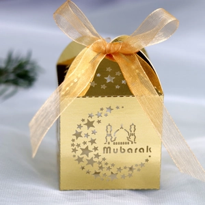 Detail of golden laser-cut candy box with moon, stars, and mosque patterns with ribbon
