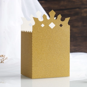 Macro shot of gold glitter cardstock gift box with crown cut-out top for wedding parties