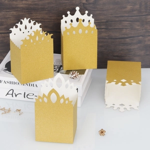 Detail of glitter gold crown hollow candy boxes for wedding parties on a wooden surface
