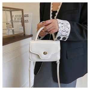 Detail of white vintage saddle bag with gold swivel clasp and detachable strap held by model