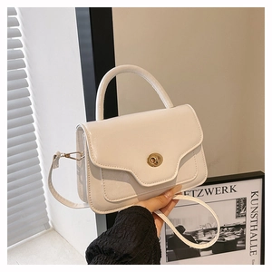 Detailed view of white glossy saddle bag featuring a wave edge and golden twist lock