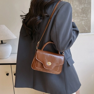 Vintage brown leather saddle bag with top handle and metallic rotating lock closure