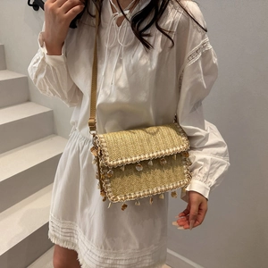 Bohemian beige woven straw crossbody bag with decorative fringe and shells for beach wear