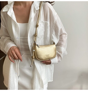 Detailed view of champagne gold crescent bag with lychee texture and knotted shoulder strap