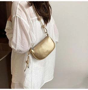 Detail of a golden dumpling bag with lychee texture and knot shoulder strap detail