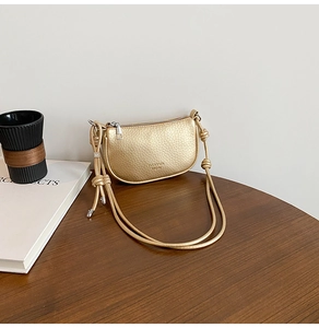Detail of gold lychee pattern leather shoulder bag with zipper on wooden table