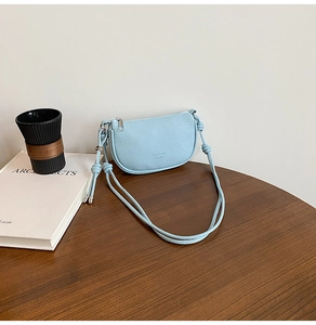 Detail of light blue lychee pattern leather handbag with knotted rope shoulder strap