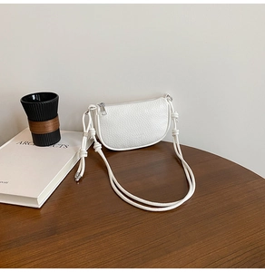 Detail of white lychee leather texture on crossbody bag with rope strap and silver zipper