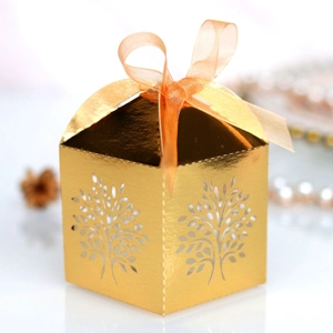Detailed laser-cut tree design on gold wedding favor box with orange ribbon