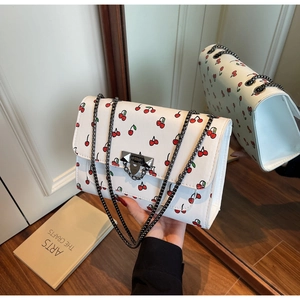 Détail du sac à bandoulière blanc imprimé cerises avec chaîne et boucle à clous