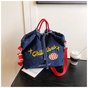 Detail of blue denim tote with red rope handles and embroidered Chill Vibes text