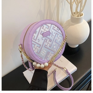 Detail of purple circular bag showing floral embroidery, gold chain, and pearl accents