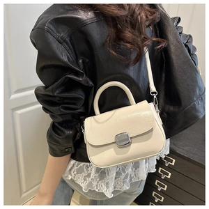 Detail of minimalist cream square handbag with silver metal buckle and top handle