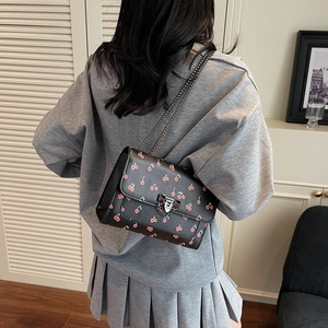 Sac à bandoulière tendance à imprimé cerise avec chaîne en métal porté par un mannequin