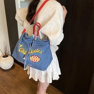 Blue denim drawstring crossbody bag with red handle and Chill Vibes embroidery